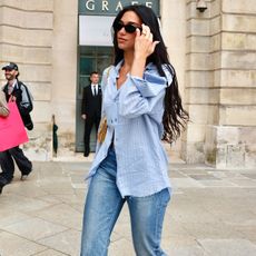 Dua Lipa in Paris wearing light-wash denim and a blue button-down with open-toe mules. 