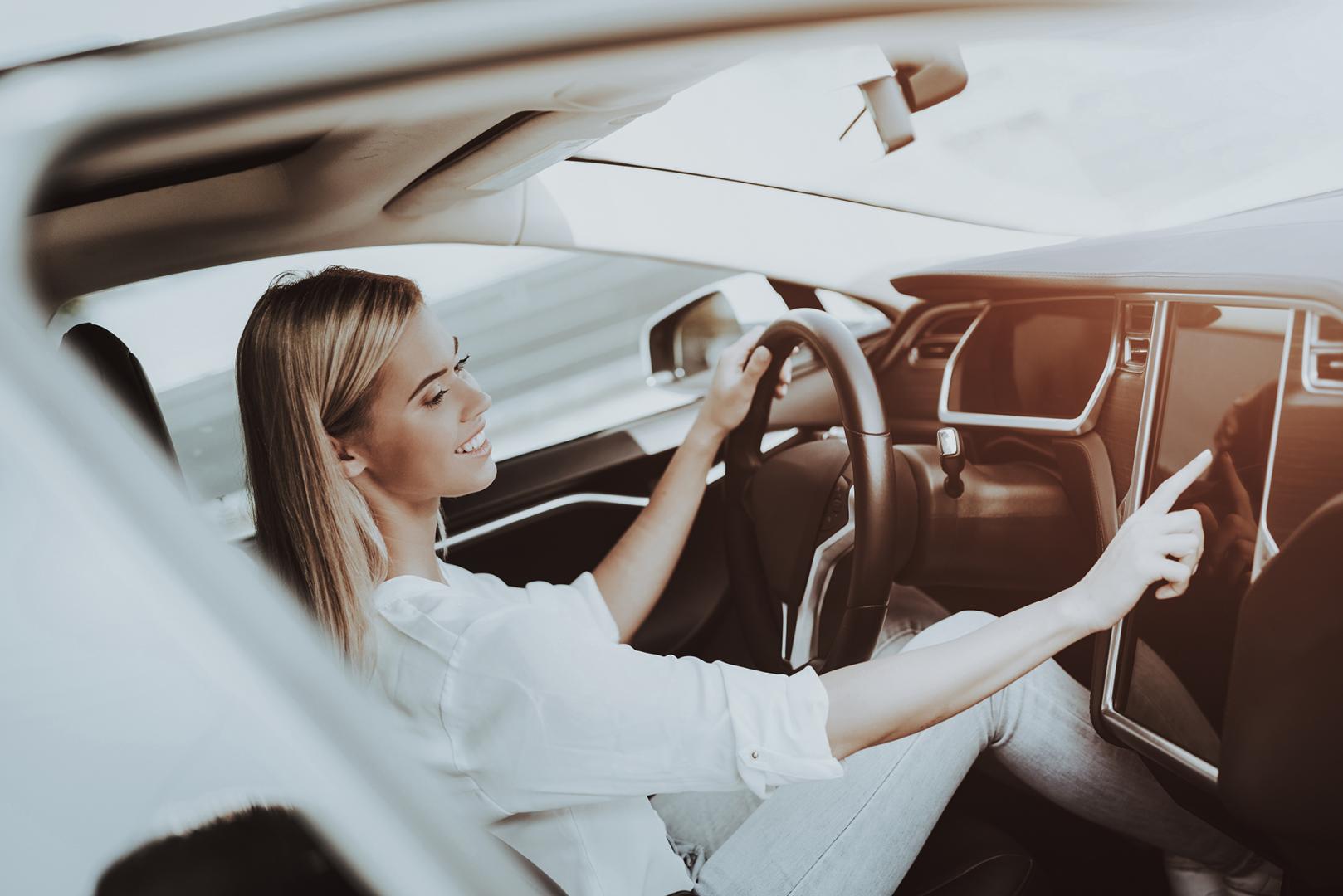 Eine Frau sitzt in einem Tesla und bedient das Tablet