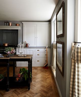 Grey kitchen walls with parquet flooring and gingham blinds.
