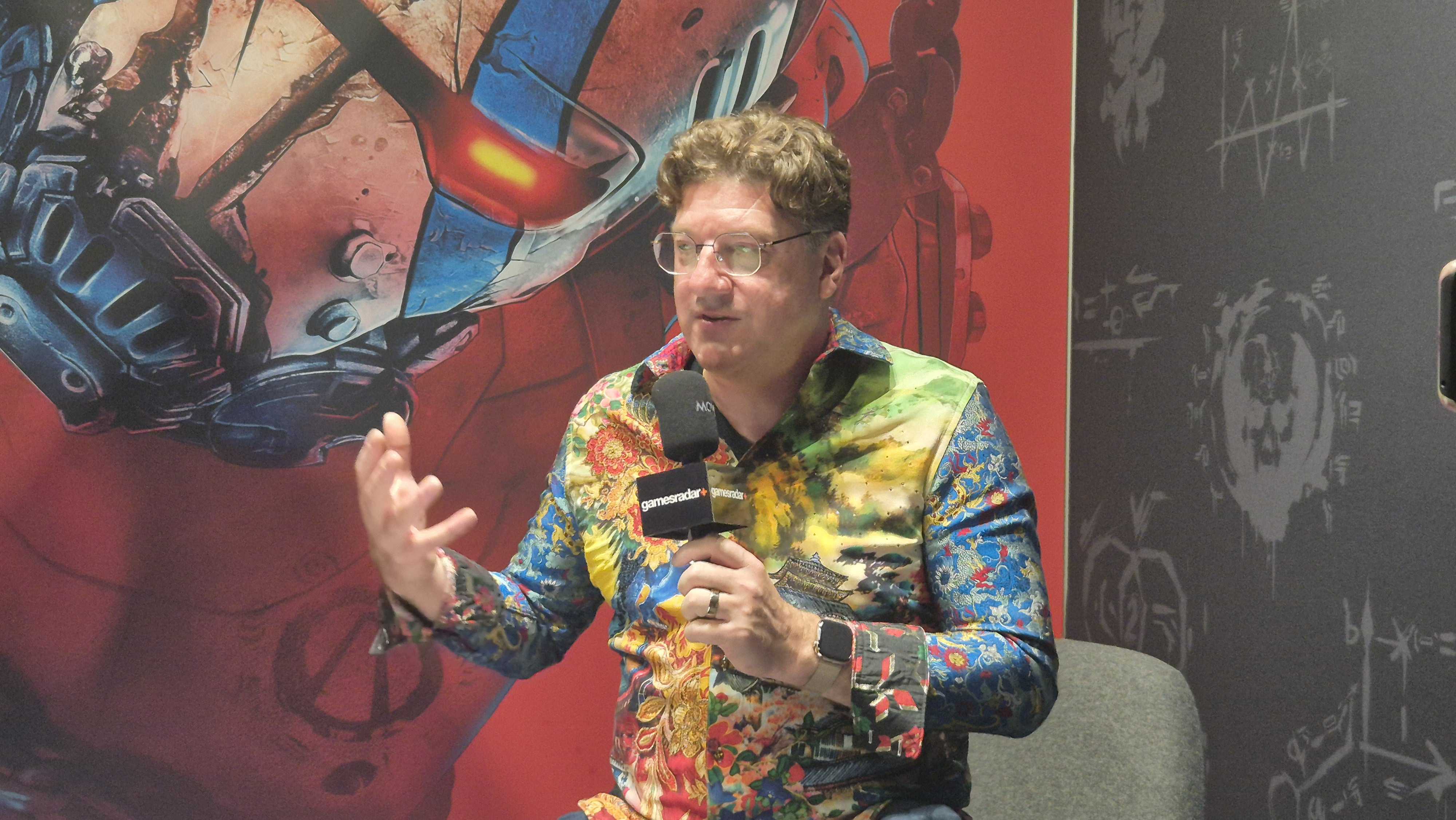 Randy Pitchford talks animatedly about Borderlands 4 in front of a bright red backdrop of the game, taken from our Borderlands 4 video interview