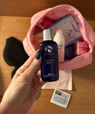 Marisa holding iS Clinical Cleansing Complex above her travel skin-care bag