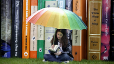 Girl reading a book under an umbrella at Hay festival