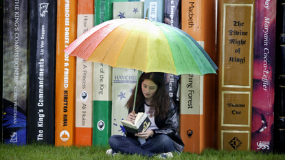 Girl reading a book under an umbrella at Hay festival