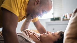 couple lying down on the bed laughing and smiling to illustrate the broken eagle sex position