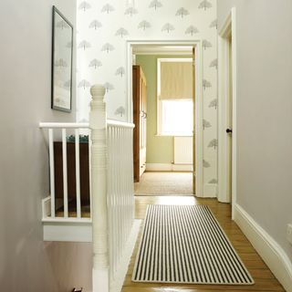 hallway with white wall and wallpaper with carpet on floor