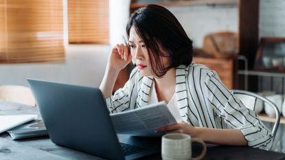 A worried female investor studies her laptop.