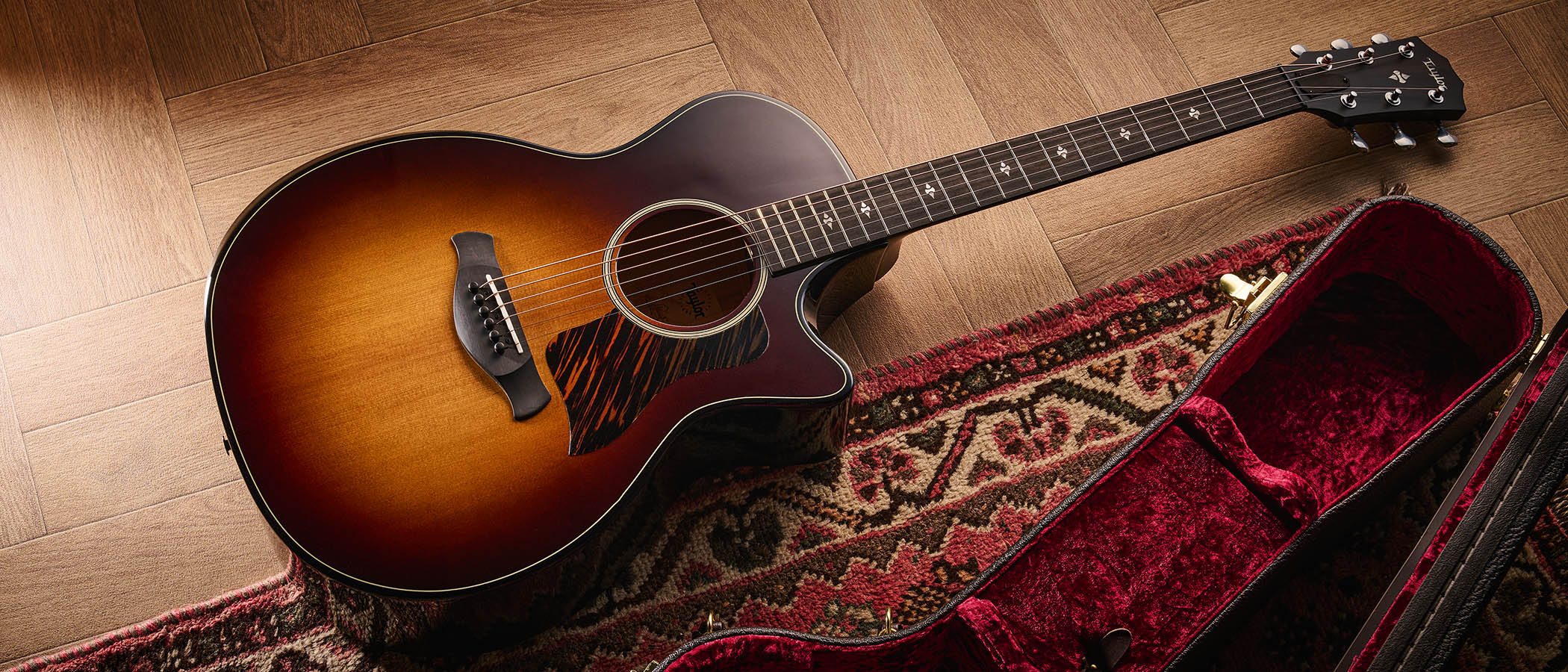 Taylor Builder’s Edition 514ce Kona Burst pictured against a wooden floor and patterned rug.