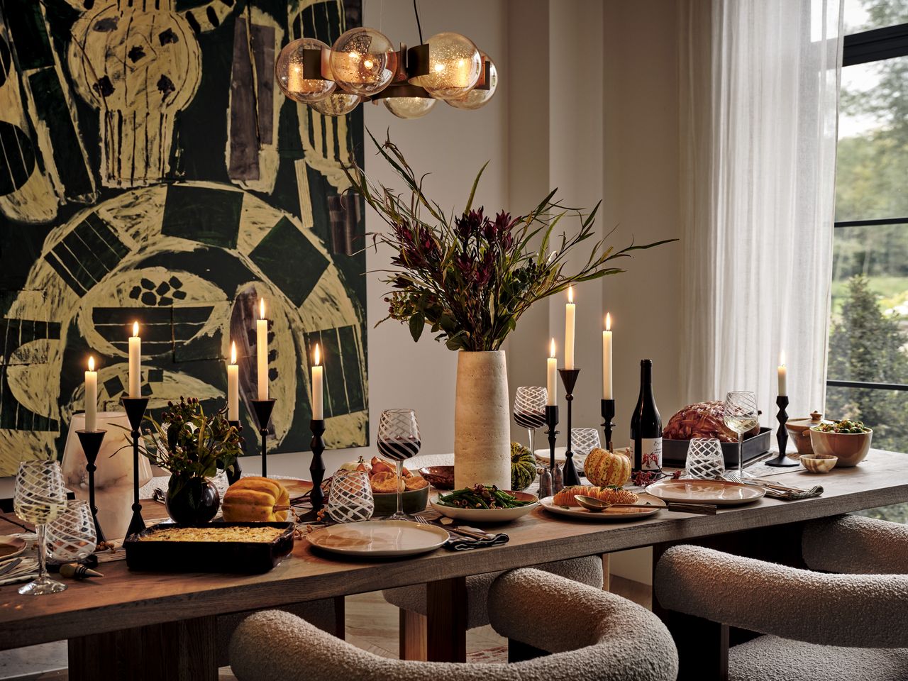 A table laid for dinner with boucle armchairs and decorated with candles 