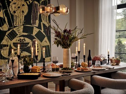 A table laid for dinner with boucle armchairs and decorated with candles 
