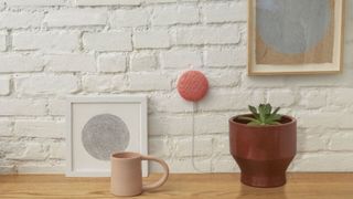Google Nest Mini mounted to white brick wall above sideboard