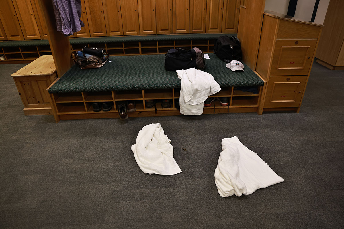 Towels strewn over the floor in the golf locker room, with hats, bags and shoes also visible around the room