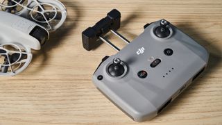 A gray DJI Neo drone with a camera sitting next to a gray RC-N3 controller