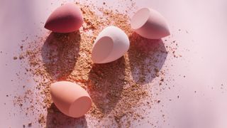 pink makeup sponges on pale pink background with powder foundation