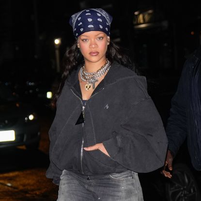 A woman wearing a bandana hair scarf wearing a zip up hoodie, multiple diamond chains, and lipgloss