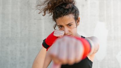 A young woman has her fists up, ready to fight inflation's impact on her portfolio.