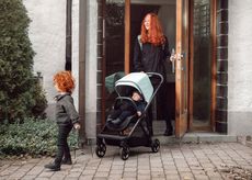 A smiling woman pushes a baby in the Thule Shine pushchair