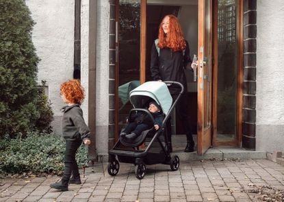 A smiling woman pushes a baby in the Thule Shine pushchair