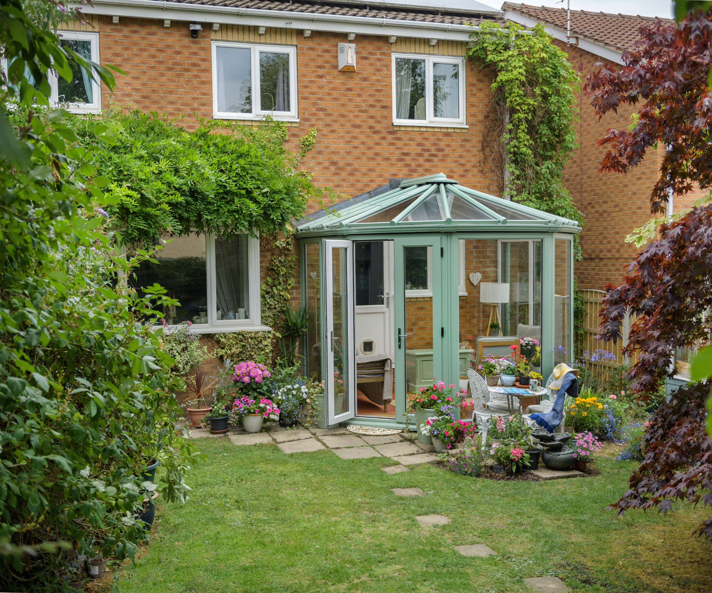 small green conservatory on back of brick property