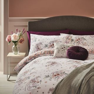 bedroom with teal pink and cream colour wall and bed with dragon printed blanket and pillow with bedside table