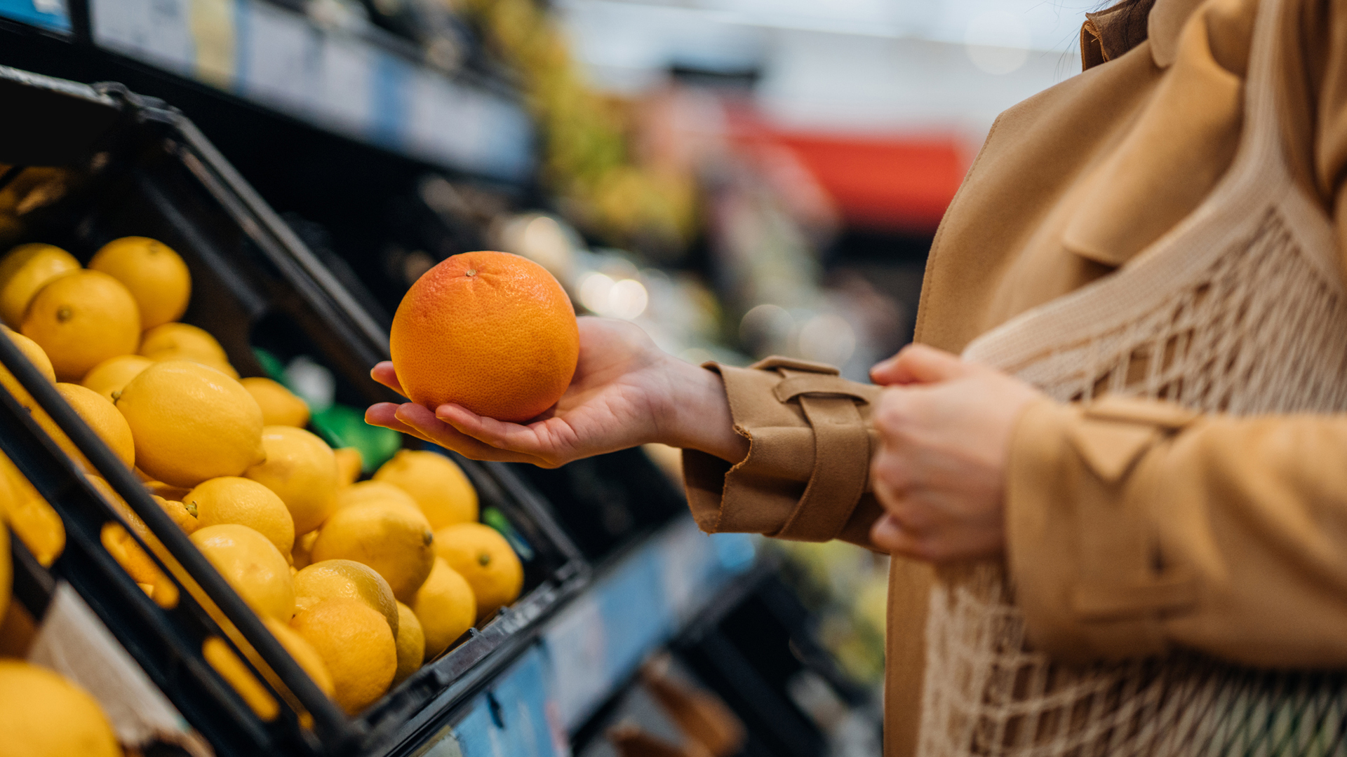 woman holding an orange at the supermarket