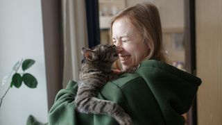 Woman holding cat with their noses touching