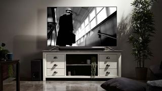 Yamaha YAS-209 on TV stand with screen above showing black and white movie image