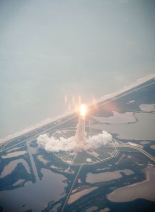Space shuttle Atlantis is seen through the window of a Shuttle Training Aircraft (STA) as it launches from Launch Pad 39A at NASA's Kennedy Space Center on the STS-135 mission, July 8, 2011 in Cape Canaveral, Fla., on the final shuttle mission.