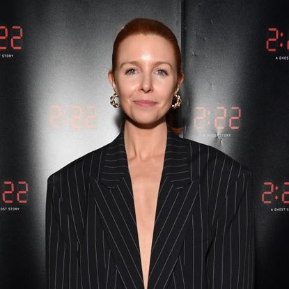 Stacey Dooley posing in a black pinstriped blazer at an event