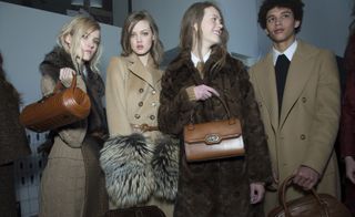 4 Models wearing beige and brown variations of formal and winter attire with matching brown bags