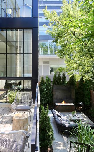 steel outdoor fireplace on a decking with an outdoor sofa in a city backyard