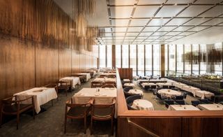 A view of the Grill Room from the north-east corner mezzanine (once derided as ’Social Siberia’ by gossip columnists). The mezzanine space features ’The Chair’, Hans Wegner’s archetypal design in leather and teak. Beyond, the room features custom banquettes designed by Johnson, and Mies’ custom ’Brno’ chairs. The French walnut panelling and Richard Lippold’s hanging sculpture will remain in the space in its next iteration