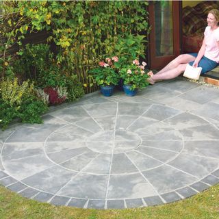 grey circular patio in lawned garden