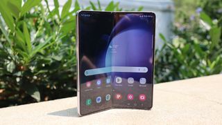 Samsung Galaxy Z Fold 5 står uppställd på en vit stenmur.