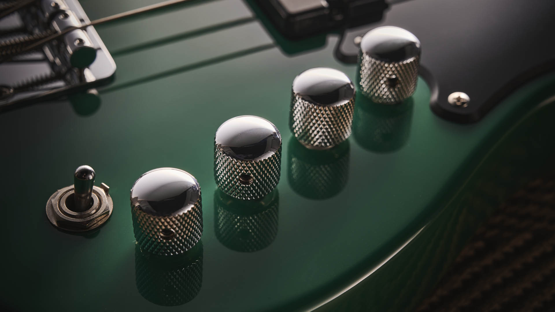 The Cort GB Short-Scale Bass finished in green, photographed against a light wooden floor and rug.