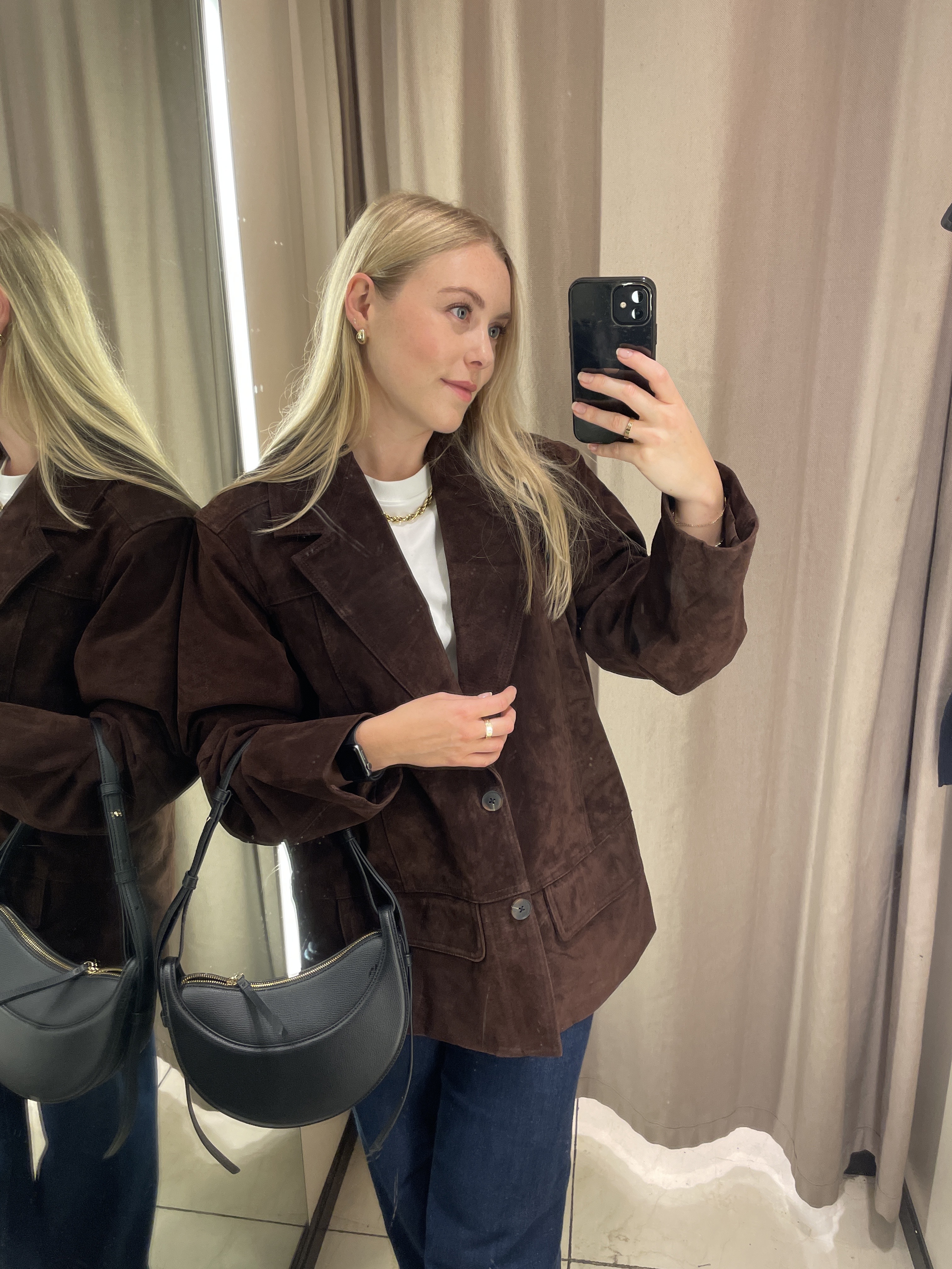 Woman in mirror wears brown suede jacket, White T-shirt and blue jeans