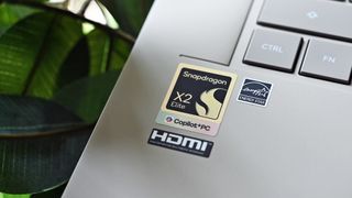 Close-up of a silver laptop deck featuring a Snapdragon X2 Elite Copilot+PC sticker alongside Energy Star and HDMI badges.