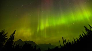 The Northern Lights appear in the sky through a layer of smoke caused by multiple wildfires in the early hours of September 4, 2022 in Banff National Park, Alberta, Canada.
