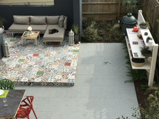 how to design an outdoor kitchen: patterned paving with garden seating and an outdoor kitchen area