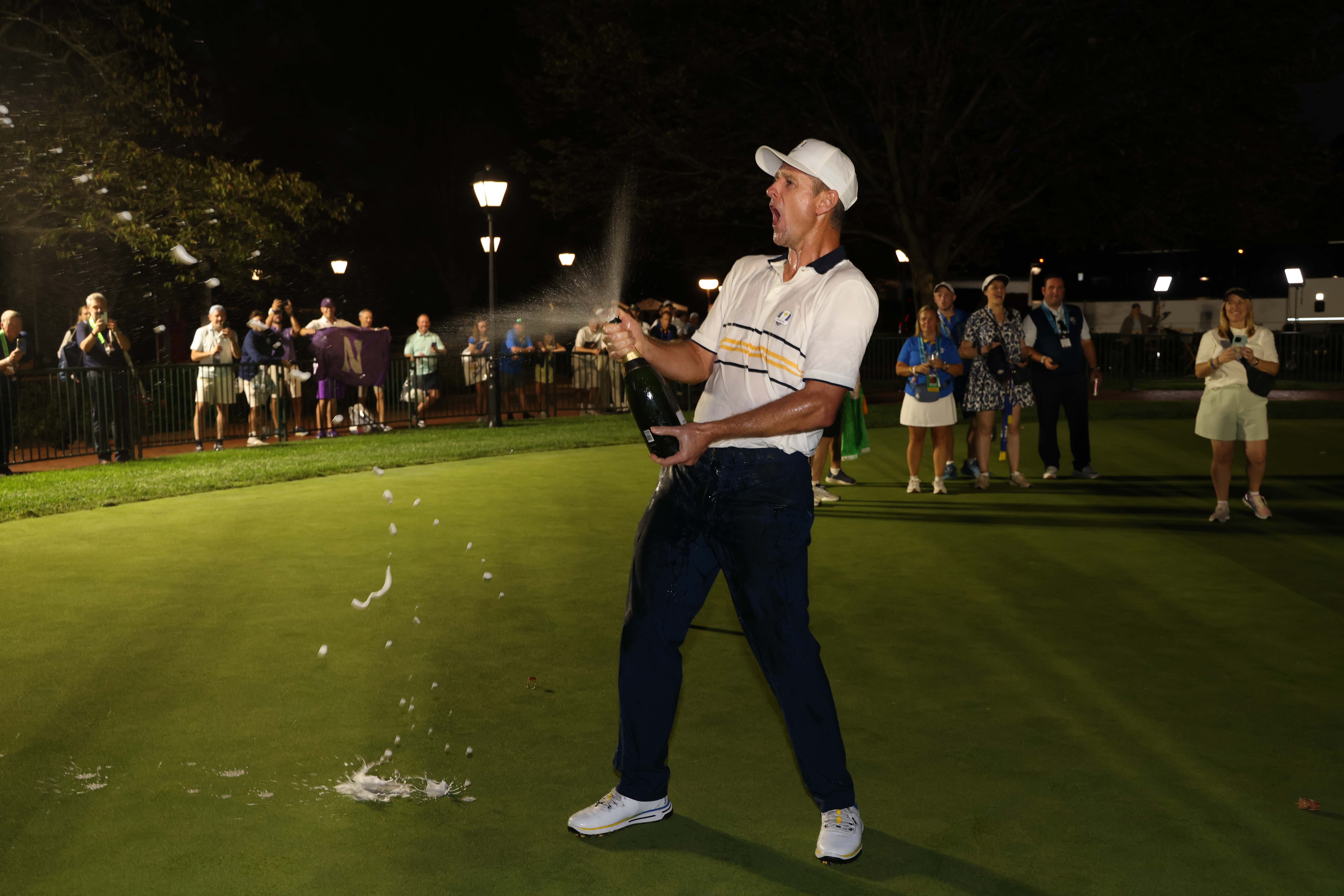 Justin Rose pops a champagne bottle and begins spraying it after Team Europe won the 2025 Ryder Cup