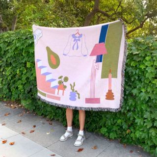 A pink patterned throw being held up outside