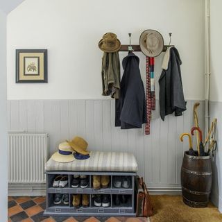 Entryway with half wall wood paneling, coat hooks and shoe storage