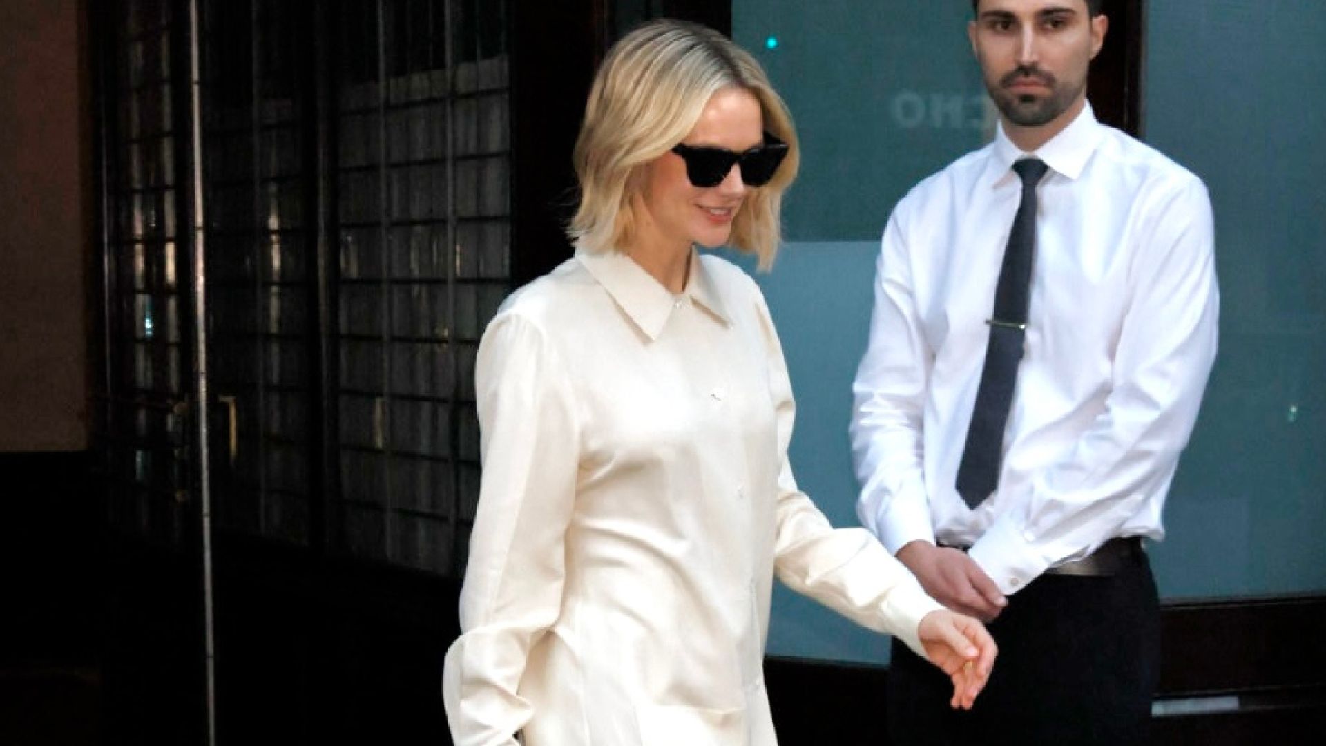 Carey Mulligan steps outside wearing cream trousers with a matching top and black sandals.