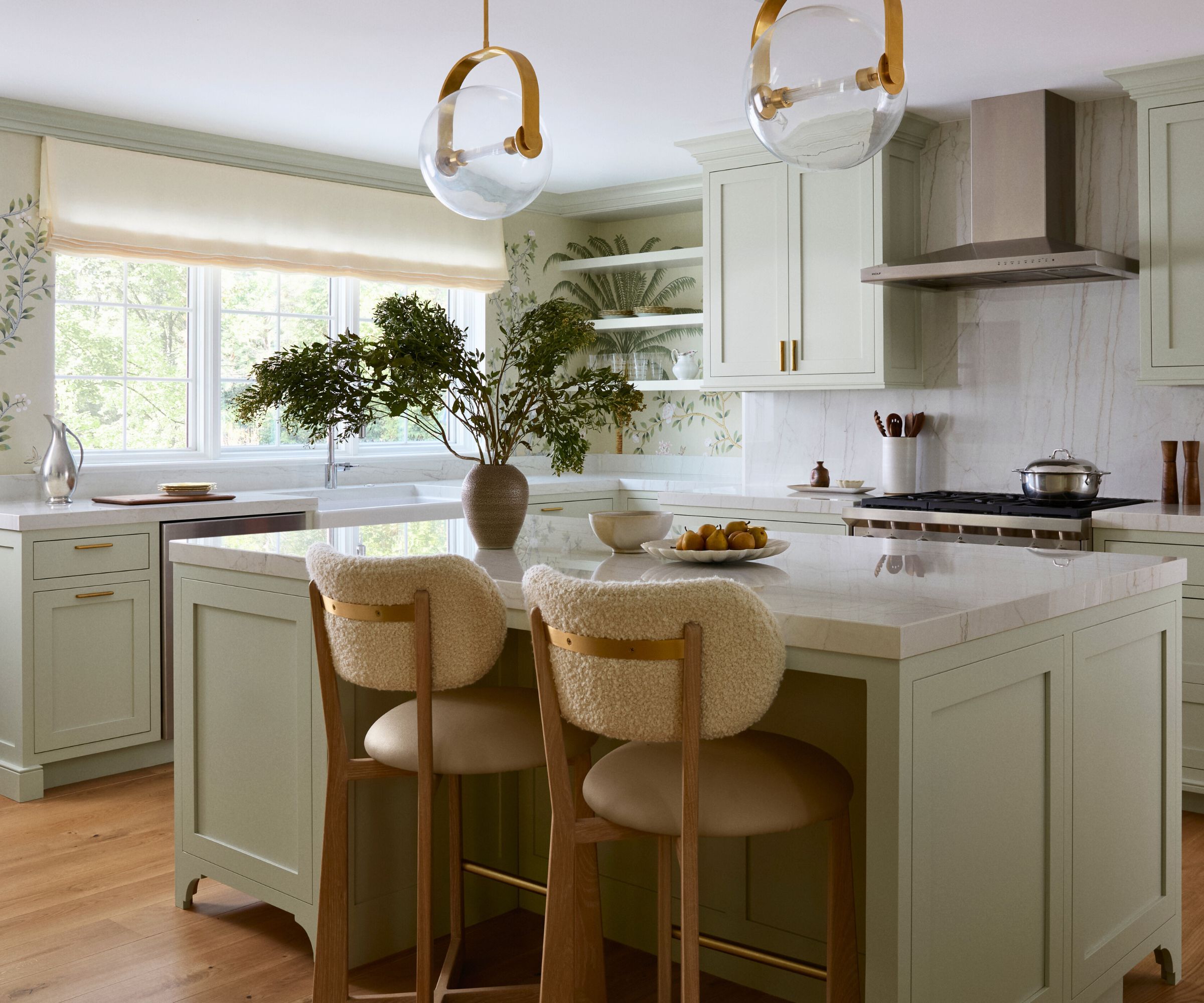 kitchen with leafy wallpaper and pale green cabinets and a island with white marble countertop