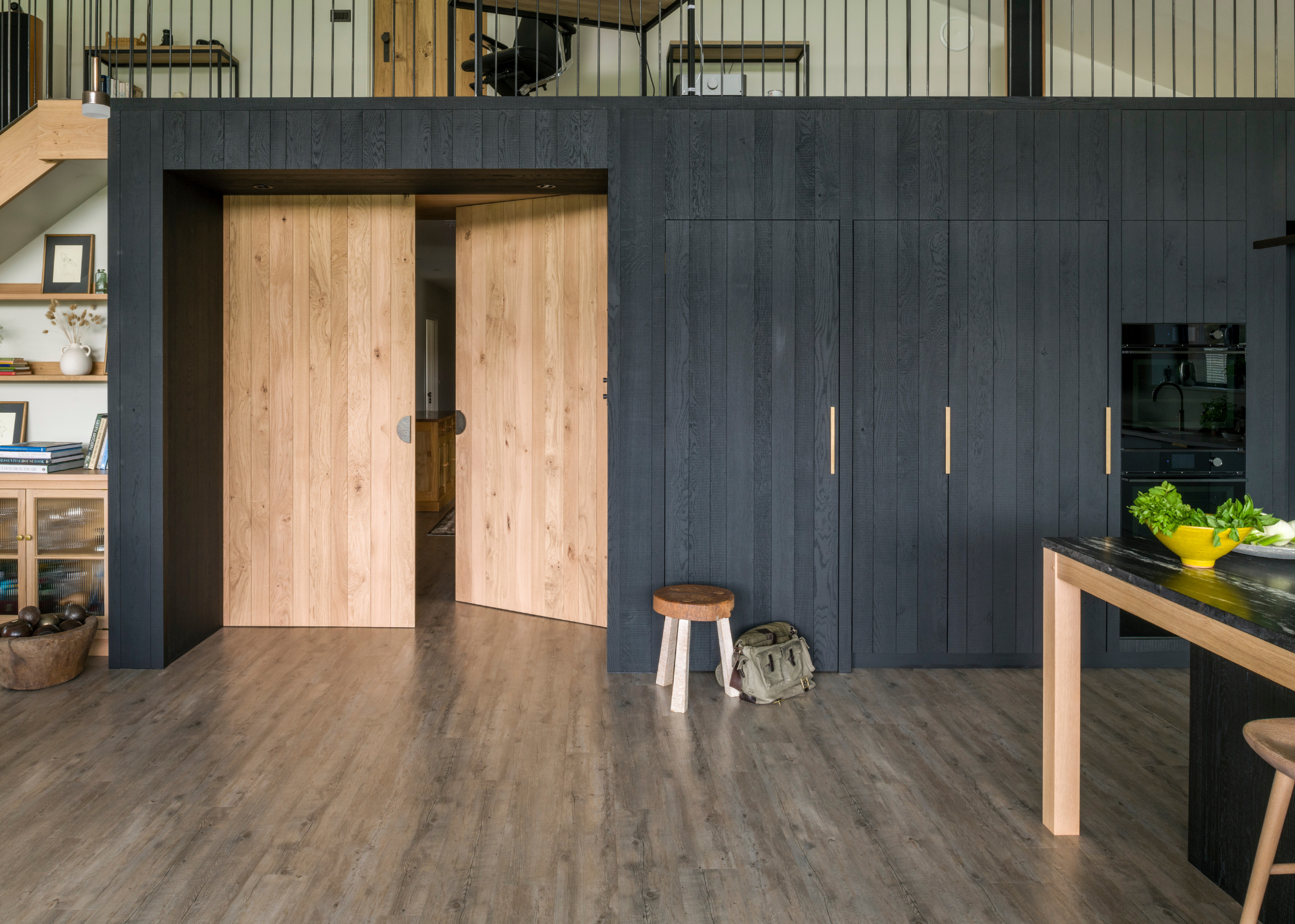 light wooden island counter with black wooden cabinetry and walls