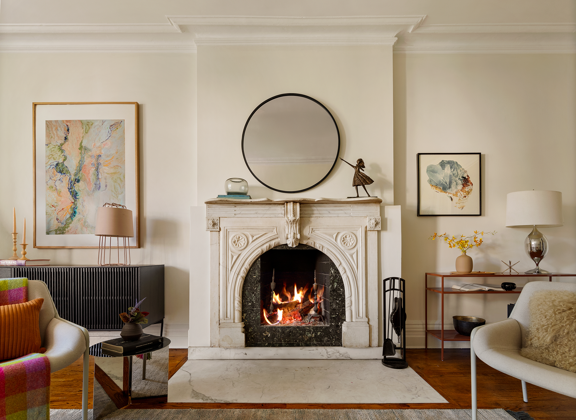 A light, neutral living space with a traditional open fire and fireplace, modern furniture and styling.