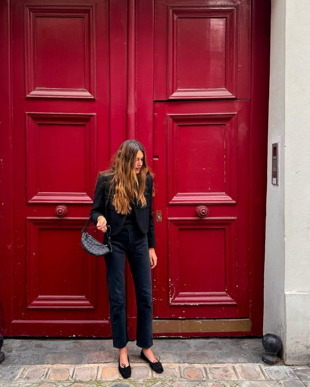 Influencer @saraloura wears black jeans with a bouclé jacket and black ballet flats.