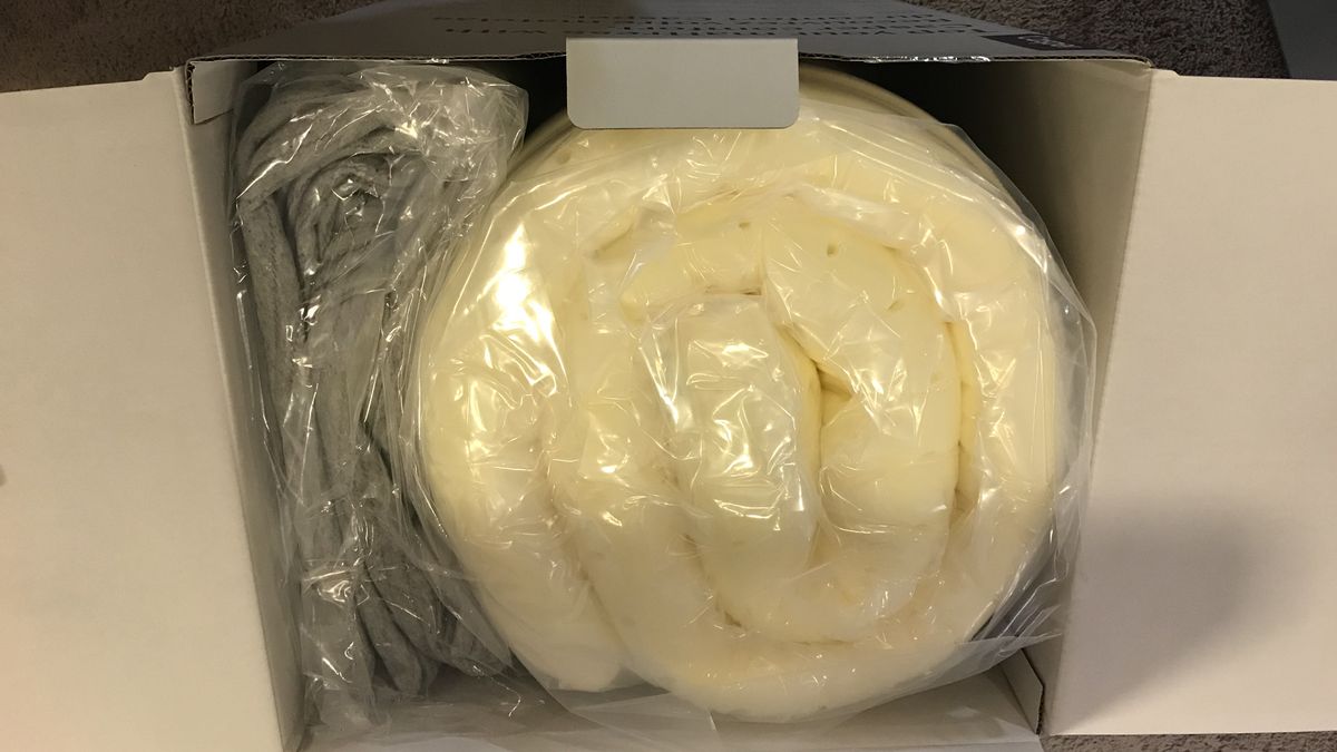 The Casper Comfy Mattress Topper rolled up into a shipping box.