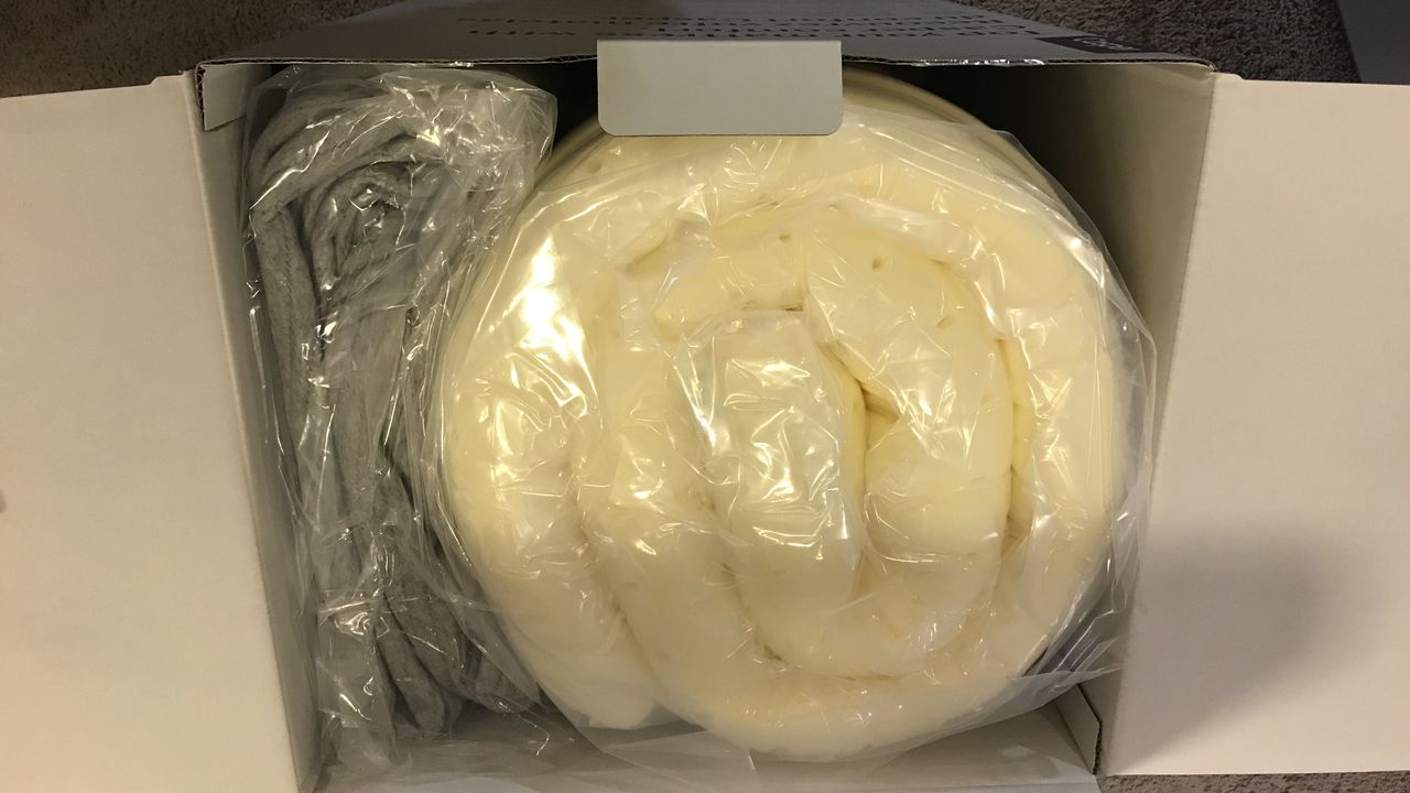 The Casper Comfy Mattress Topper rolled up into a shipping box.