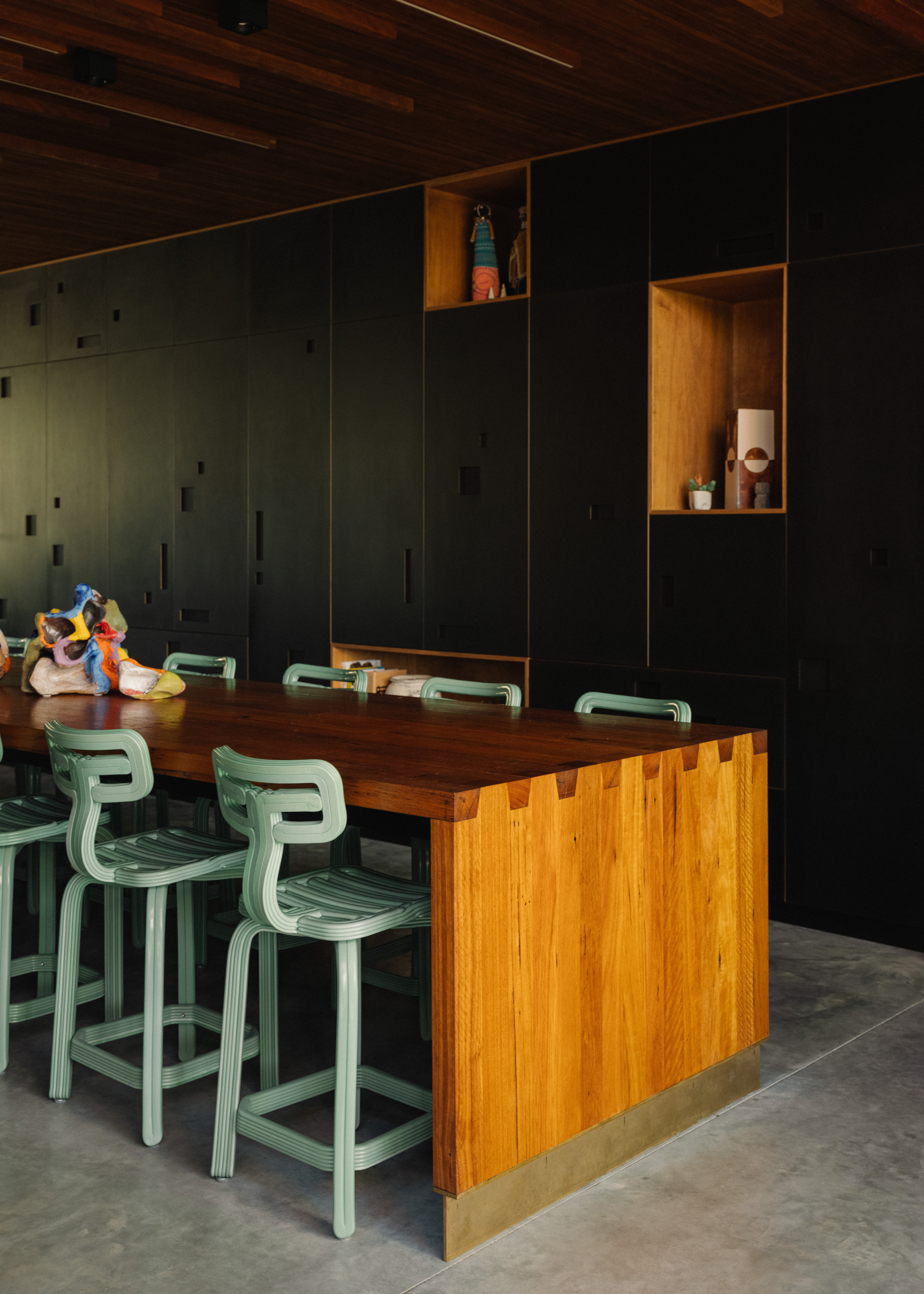 A long wood dining table with mint green stools