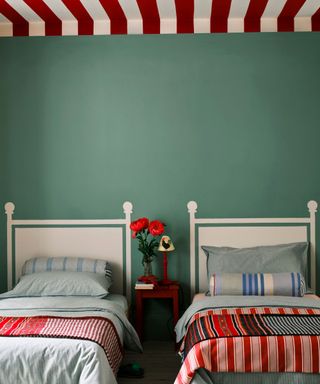 child's bedroom with twin beds, green walls, red and white striped ceiling and white headboards painted onto wall